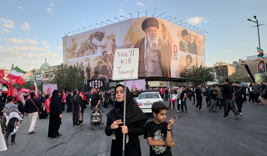 A woman holds a sign reading "We'll Kill Trump" while waiting in Islamic Revolution Square for the funeral procession of the slain Iranian Supreme Leader Ayatollah Ali Khamenei beneath a billboard depicting Khamenei in Tehran, Iran, Monday, July 6, 2026. (AP Photo/Altaf Qadri)