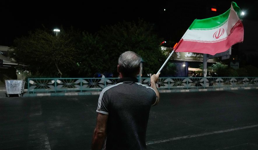 A pro-government demonstrator waves an Iranian flag in a gathering commemorating the late Iranian Supreme Leader Ayatollah Ali Khamenei at a square in Tehran, Iran, Saturday, July 11, 2026. (AP Photo/Vahid Salemi)