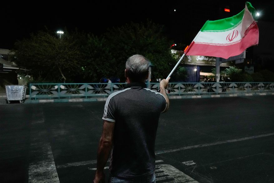 A pro-government demonstrator waves an Iranian flag in a gathering commemorating the late Iranian Supreme Leader Ayatollah Ali Khamenei at a square in Tehran, Iran, Saturday, July 11, 2026. (AP Photo/Vahid Salemi)