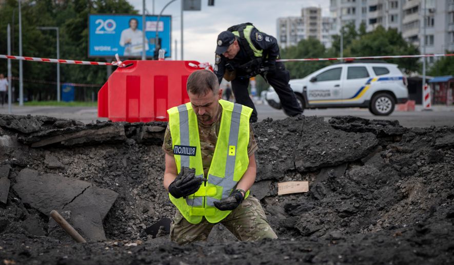 A sapper examines the impact site of a Russian missile in a residential area of Kyiv, Saturday, July 11, 2026. (AP Photo/Dan Bashakov)