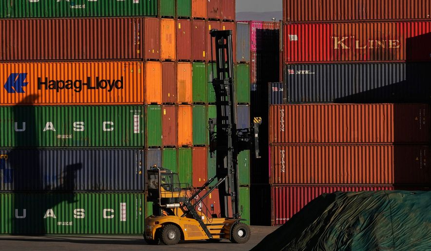 A heavy machine drives past shipping containers stacked at a depo, in Johannesburg, South Africa, Friday, Aug. 1, 2025. (AP Photo/Themba Hadebe, File)