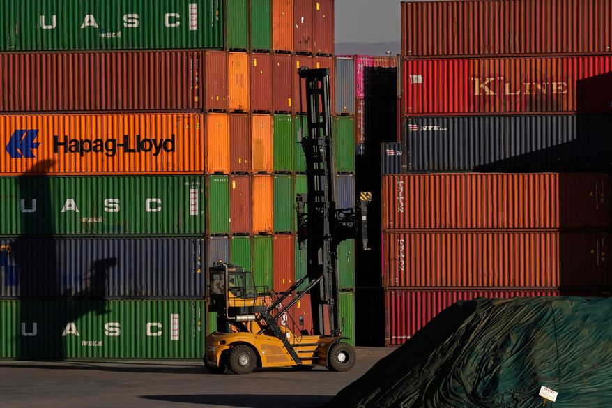 A heavy machine drives past shipping containers stacked at a depo, in Johannesburg, South Africa, Friday, Aug. 1, 2025. (AP Photo/Themba Hadebe, File)
