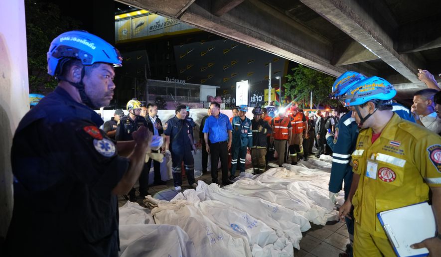 Thailand Prime Minister Anutin Charnvirakul, in blue, inspects the site of a fire as bodies of victims are laid in a row in Bangkok, Thailand, Monday, July 13, 2026. (AP Photo/Sakchai Lalit)