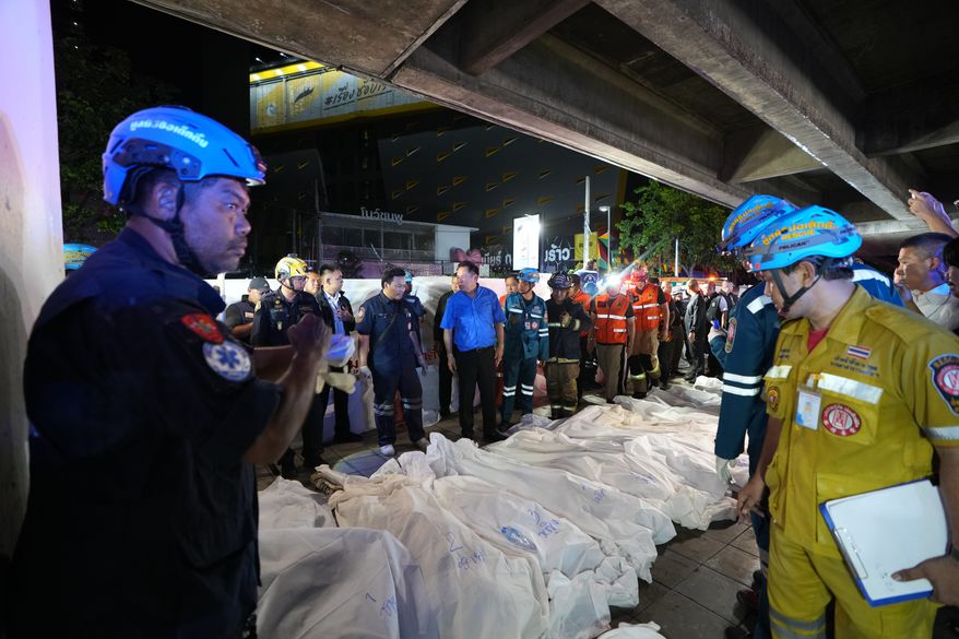 Thailand Prime Minister Anutin Charnvirakul, in blue, inspects the site of a fire as bodies of victims are laid in a row in Bangkok, Thailand, Monday, July 13, 2026. (AP Photo/Sakchai Lalit)