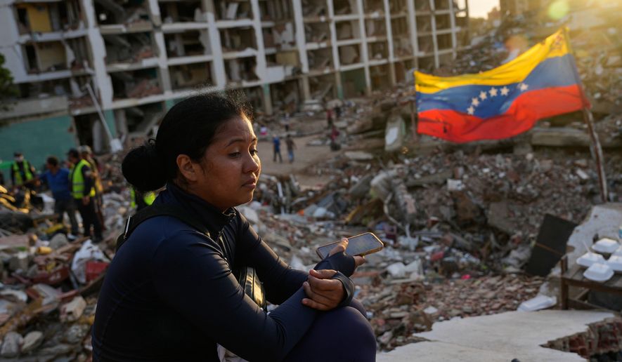 Estefany Landaez sits amid the rubble of a building, waiting to find her two children after the earthquakes in La Guaira, Venezuela, Sunday, July 12, 2026. (AP Photo/Ariana Cubillos)