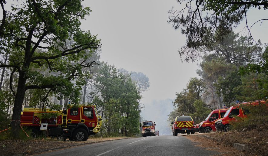 Fire trucks are parked near the scene of a wildfire in the region of the historic Fontainebleau forest, about 60 km (37 miles) south of Paris, France, Monday, July 13, 2026. (AP Photo/Emma Da Silva)