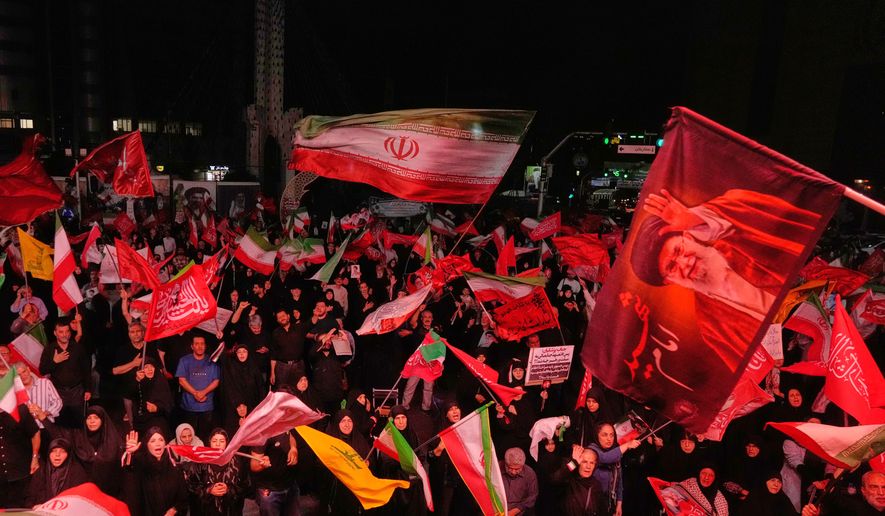 Pro-government demonstrators wave Iranian and religious flags in a gathering commemorating the late Iranian Supreme Leader Ayatollah Ali Khamenei, shown in a flag at right, at a square in Tehran, Saturday, July 11, 2026. (AP Photo/Vahid Salemi)