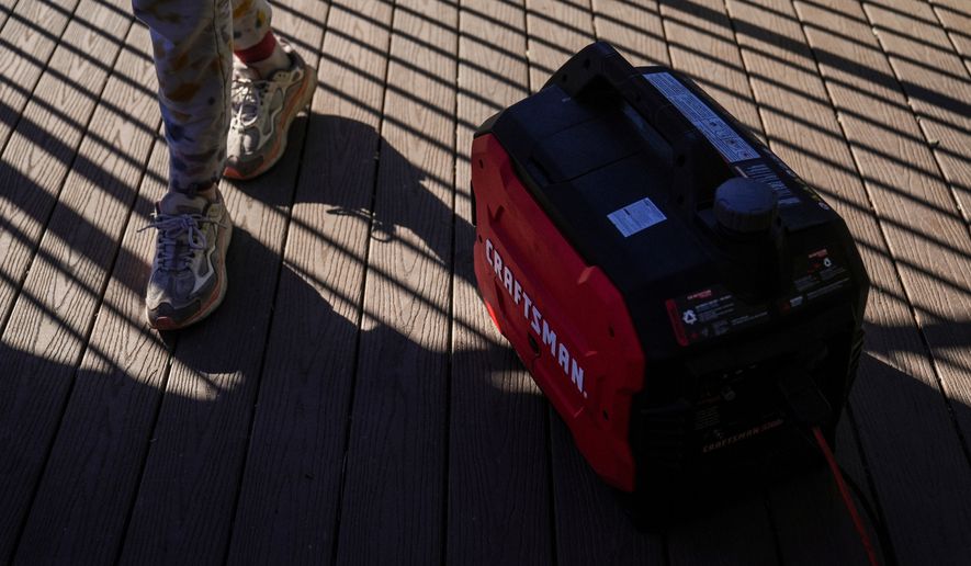 FILE - Kaylin Johnson, whose home is one of the few that survived the Eaton Fire in her neighborhood in Altadena, Calif., walks past a generator running to provide power at her home Jan. 14, 2025. (AP Photo/Jae C. Hong, File)