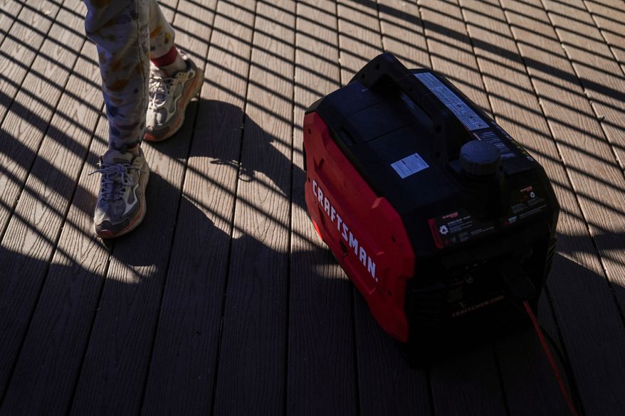 FILE - Kaylin Johnson, whose home is one of the few that survived the Eaton Fire in her neighborhood in Altadena, Calif., walks past a generator running to provide power at her home Jan. 14, 2025. (AP Photo/Jae C. Hong, File)