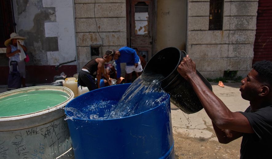 People collect water from a street tap during a blackout in Havana, Cuba, Tuesday, July 14, 2026. (AP Photo/Ramon Espinosa)