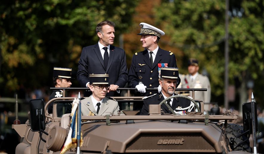 French President Emmanuel Macron, left, stands in the command car with General Chief of Staff of the French Armed Forces Fabien Mandon during the annual Bastille Day military parade on the Champs-Elysees avenue in Paris, France, Tuesday, July 14, 2026. (Benoit Tessier/Pool Photo via AP)