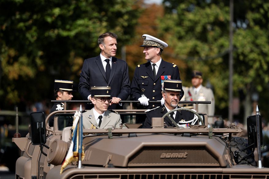 French President Emmanuel Macron, left, stands in the command car with General Chief of Staff of the French Armed Forces Fabien Mandon during the annual Bastille Day military parade on the Champs-Elysees avenue in Paris, France, Tuesday, July 14, 2026. (Benoit Tessier/Pool Photo via AP)