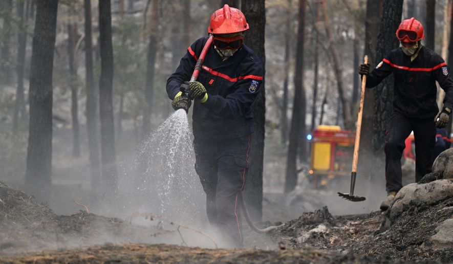 A firefighter sprays water after a wildfire in the region of the Fontainebleau forest, south of Paris, France, Tuesday, July 14, 2026. (AP Photo/Emma Da Silva)