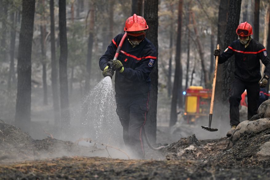 A firefighter sprays water after a wildfire in the region of the Fontainebleau forest, south of Paris, France, Tuesday, July 14, 2026. (AP Photo/Emma Da Silva)