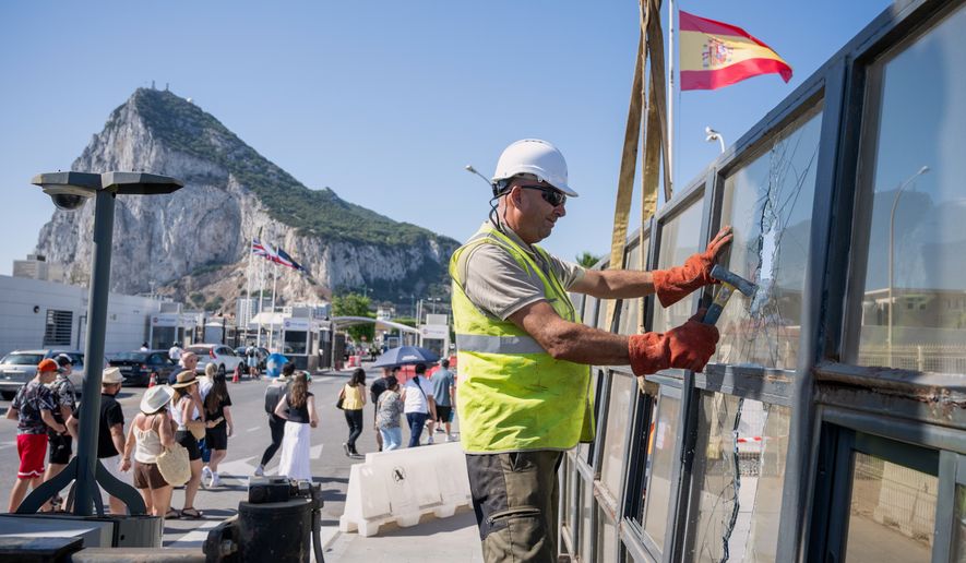 Against the backdrop of the Rock of Gibraltar, workers dismantle a Spanish border checkpoint that separated the disputed British overseas territory from Spain in La Línea de la Concepción, Spain, Monday, July 6, 2026. (AP Photo/Marcos Moreno)