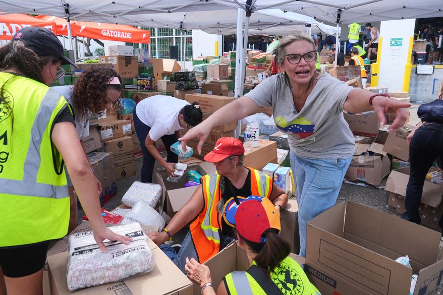 Lisa Galindez calls on other volunteers to help pack baby items at the Global Empowerment Mission Venezuela relief donation site Tuesday, June 30, 2026, in Doral, Fla. (AP Photo/Marta Lavandier)