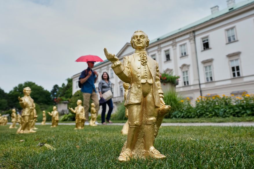 People pass 400 gold colored plastic Mozart sculptures by German artist Ottmar Hoerl from Nuremberg before the 270th birthday of composer Wolfgang Amadeus Mozart in Salzburg, Austria, Wednesday, July 15, 2026. (AP Photo/Matthias Schrader)