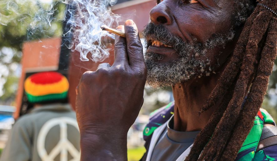 A Rastafarian smokes as they gather outside Milimani Law Courts, after the high court dismisses a Rastafarian case seeking to legalize marijuana, in Nairobi, Wednesday, July 15, 2026. (AP Photo/Andrew Kasuku)