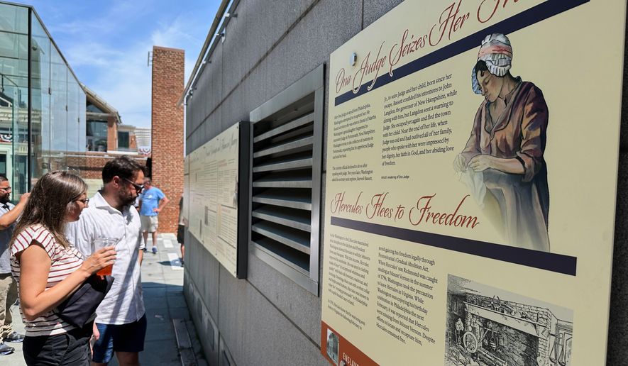 Visitors view the reinstalled educational panels about slavery at the site of President George Washington's home in Philadelphia, Wednesday, July 15, 2026. (AP Photo/Tassanee Vejpongsa)
