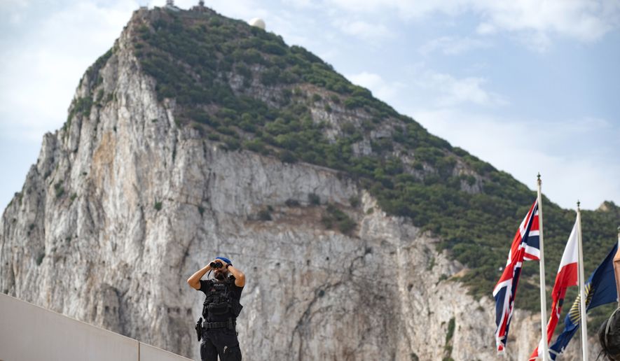A Spanish police officer uses a pair of binoculars on the first day of passport-free travel under a new EU-U.K. treaty, at the border crossing between Gibraltar and Spain in La Línea de la Concepción, Spain, Wednesday, July 15, 2026. (AP Photo/Marcos Moreno)