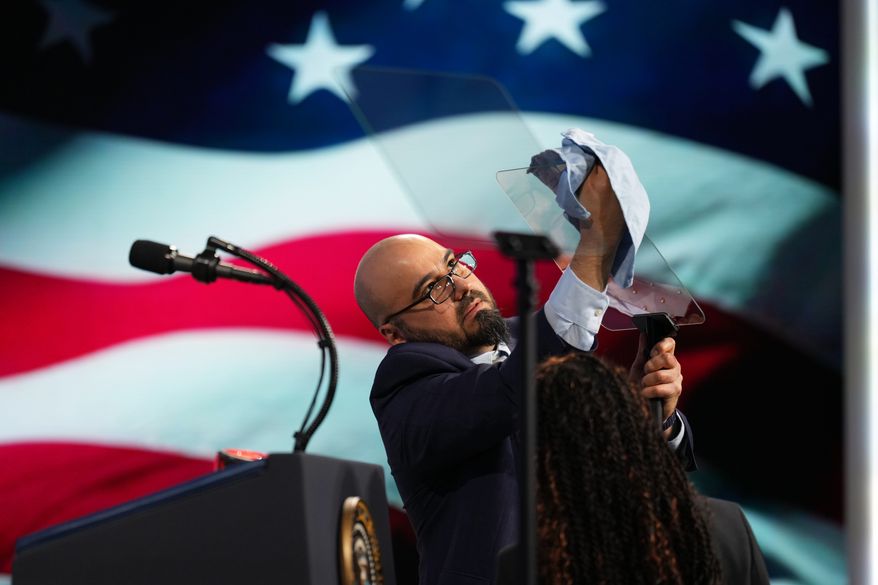 A person cleans the teleprompter before President Donald Trump speaks at the Future Investment Initiative Institute's summit Friday, March 27, 2026, in Miami Beach, Fla. (AP Photo/Mark Schiefelbein)