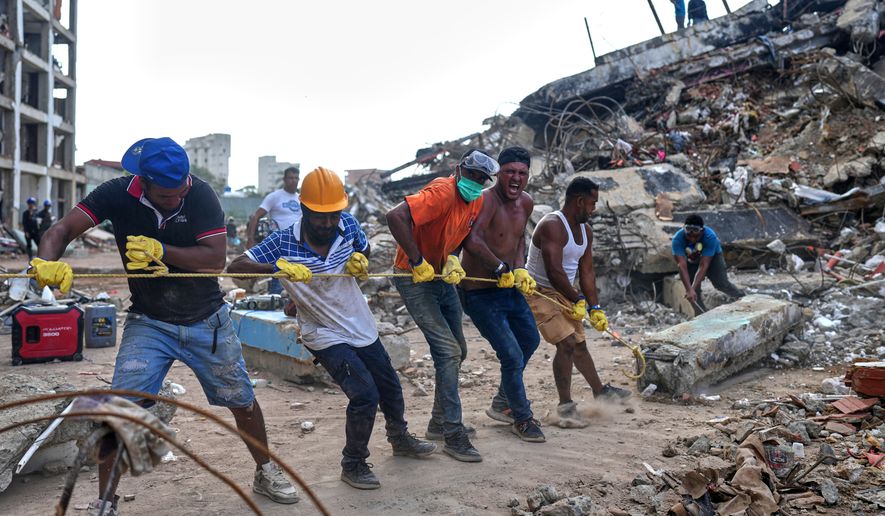 Volunteers pull a rope to remove a debris from a collapsed building by earthquakes in La Guaira, Venezuela, Sunday, July 12, 2026. (AP Photo/Ariana Cubillos)
