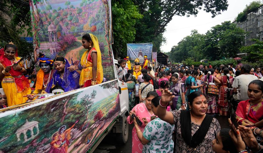 Hindu devotees gather around tableau with Hindu mythological characters Krishna and Radha as they participate in a religious procession during the Rath Yatra, or chariot festival, carrying the Hindu deities of Jagannath, Balaram and Subhadra, in Kolkata, India, Thursday, July 16, 2026. (AP Photo/Bikas Das)
