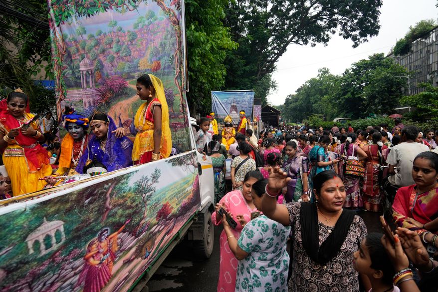 Hindu devotees gather around tableau with Hindu mythological characters Krishna and Radha as they participate in a religious procession during the Rath Yatra, or chariot festival, carrying the Hindu deities of Jagannath, Balaram and Subhadra, in Kolkata, India, Thursday, July 16, 2026. (AP Photo/Bikas Das)