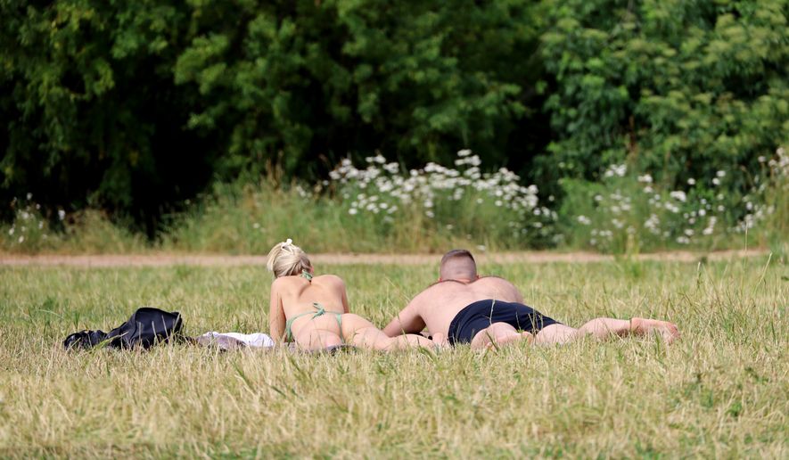 Couple sunbathing on the grass in park. File photo credit: Oleg Elkov via Shutterstock.