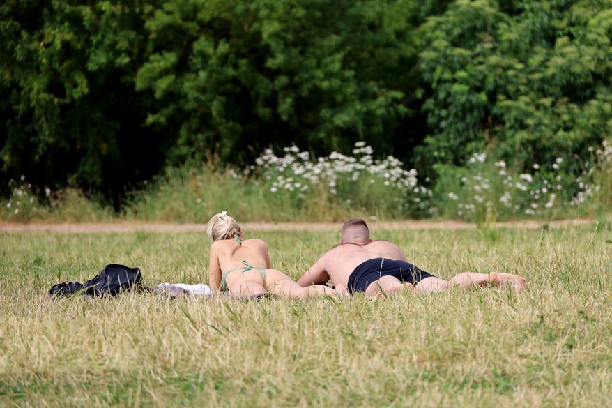 Couple sunbathing on the grass in park. File photo credit: Oleg Elkov via Shutterstock.