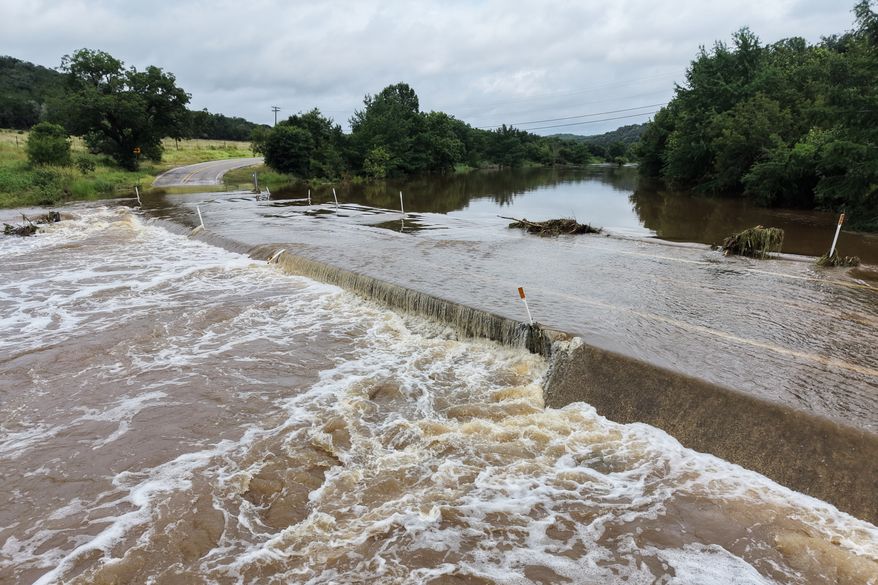 The Guadalupe River floods a crossing after a series of storms on Friday, July 17, 2026, in Hunt, Texas. (AP Photo/Gerald Herbert)