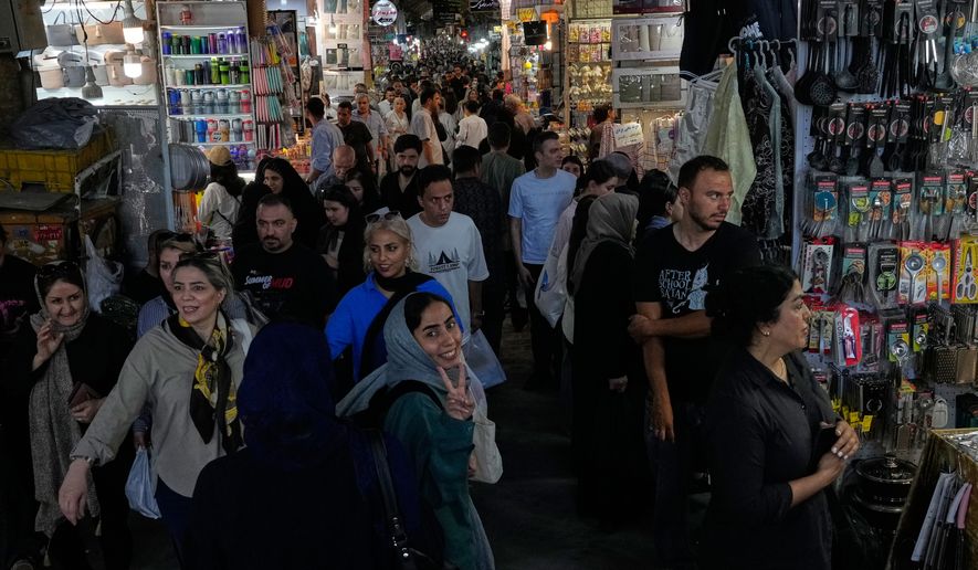 A woman flashes a victory sign while walking at Tehran's traditional main bazaar, Iran, Thursday, July 16, 2026. (AP Photo/Vahid Salemi)
