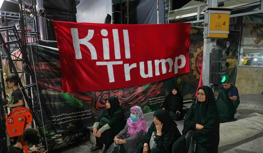 Women sit beneath a banner reading in English, "Kill Trump," during a pro-government rally in Tehran, Friday, July 17, 2026. (AP Photo/Vahid Salemi)