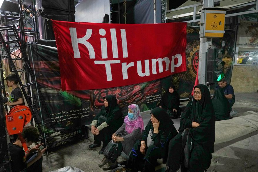 Women sit beneath a banner reading in English, "Kill Trump," during a pro-government rally in Tehran, Friday, July 17, 2026. (AP Photo/Vahid Salemi)