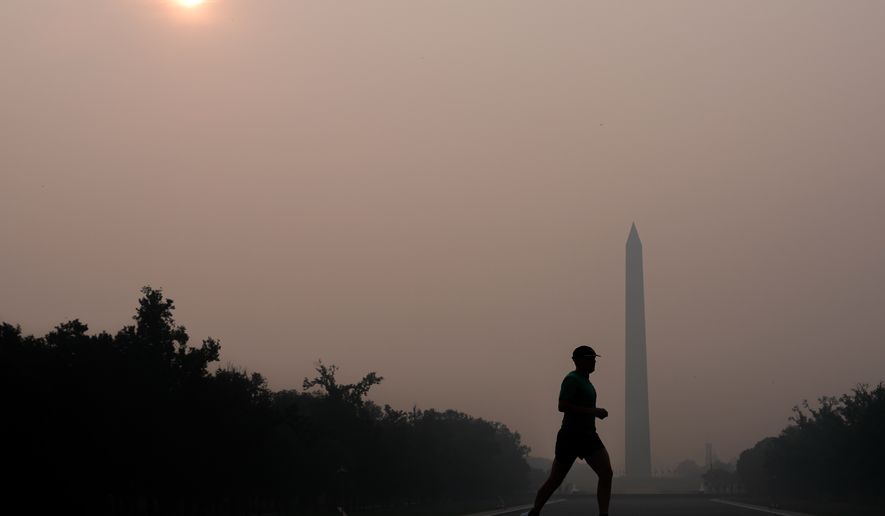 The sun is obscured by wildfire smoke as a person runs in front of the Washington Monument and Lincoln Memorial Reflecting Pool, Friday, July 17, 2026, on the National Mall in Washington. (AP Photo/Julia Demaree Nikhinson)