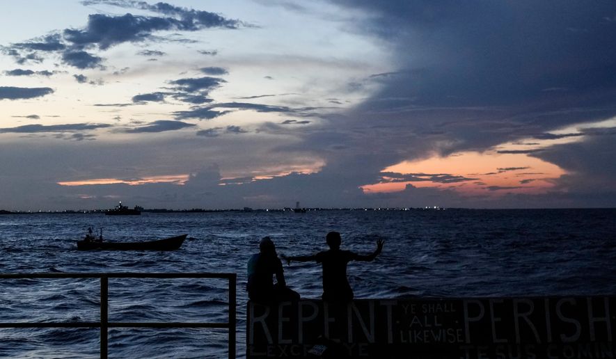 FILE - People sit on the seawall as the sun sets in Georgetown, Guyana, Tuesday, Nov. 19, 2024. (AP Photo/Matias Delacroix, File)