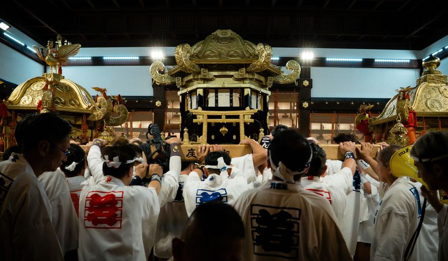Festival participants carry Yasaka Shrine's Eastern Mikoshi back into the shrine's main hall following the "Mikoshi Arai" purification ritual ahead of the Gion Matsuri festival in Kyoto, western Japan, Friday, July 10, 2026. (AP Photo/Fred Mery)