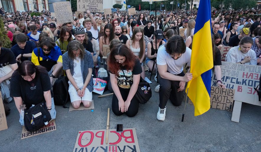 Activists kneel as they take a moment of silence to honor the fallen soldiers in Russia-Ukraine war during a rally to denounce President Volodymyr Zelenskyy's decision to dismiss Defense Minister Mykhailo Fedorov after six months in the post, in Kyiv, Ukraine, Saturday, July 18, 2026. (AP Photo/Efrem Lukatsky)