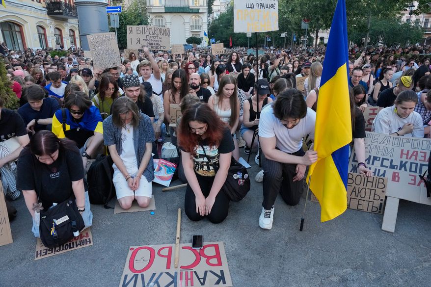 Activists kneel as they take a moment of silence to honor the fallen soldiers in Russia-Ukraine war during a rally to denounce President Volodymyr Zelenskyy's decision to dismiss Defense Minister Mykhailo Fedorov after six months in the post, in Kyiv, Ukraine, Saturday, July 18, 2026. (AP Photo/Efrem Lukatsky)