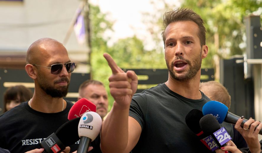 Andrew Tate, left, watches his brother Tristan speak, outside a police station in Voluntari, Romania, May 21, 2025. (AP Photo/Vadim Ghirda, File)