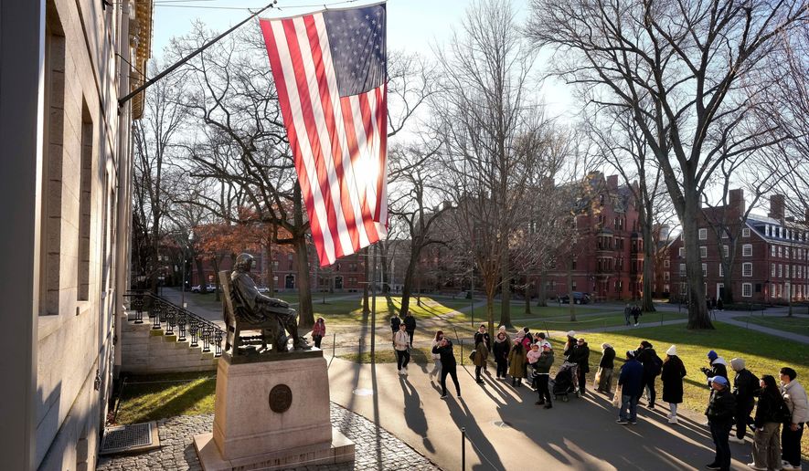 People take photos near a John Harvard statue, left, on the Harvard University campus, Jan. 2, 2024, in Cambridge, Mass. (AP Photo/Steven Senne, File)