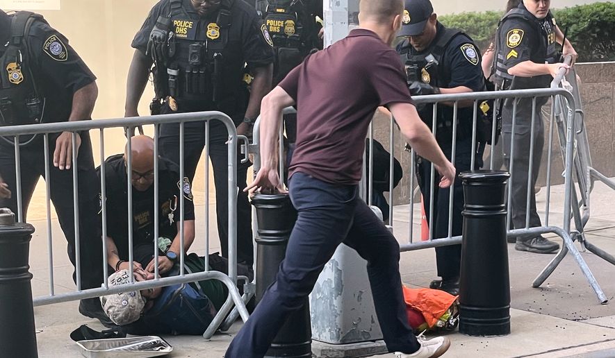 In this photo provided by Robert Sullivan several officers surround a person on the ground near the site of a fire at 26 Federal Plaza in lower Manhattan, Monday, July 20, 2026, in New York. (Robert Sullivan via AP)
