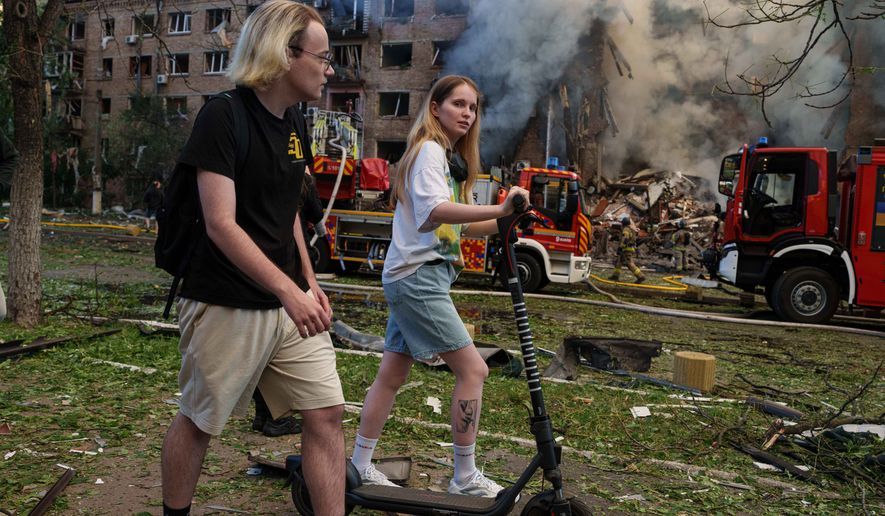 People walk past a smoldering residential building destroyed by a Russian strike in the Lukianivka neighbourhood of Kyiv, Ukraine, on Sunday, May 24, 2026. (AP Photo/Evgeniy Maloletka)
