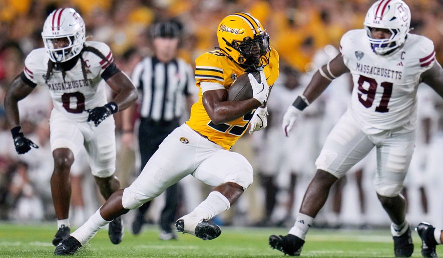 FILE - Missouri running back Ahmad Hardy, center, runs with the ball as Massachusetts defensive lineman Derrieon Craig, left, and defensive lineman Shymell Davis (91) defend during the first half of an NCAA college football game, Sept. 27, 2025, in Columbia, Mo. (AP Photo/Jeff Roberson, File)