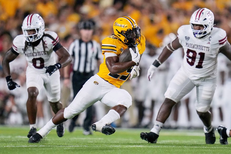 FILE - Missouri running back Ahmad Hardy, center, runs with the ball as Massachusetts defensive lineman Derrieon Craig, left, and defensive lineman Shymell Davis (91) defend during the first half of an NCAA college football game, Sept. 27, 2025, in Columbia, Mo. (AP Photo/Jeff Roberson, File)