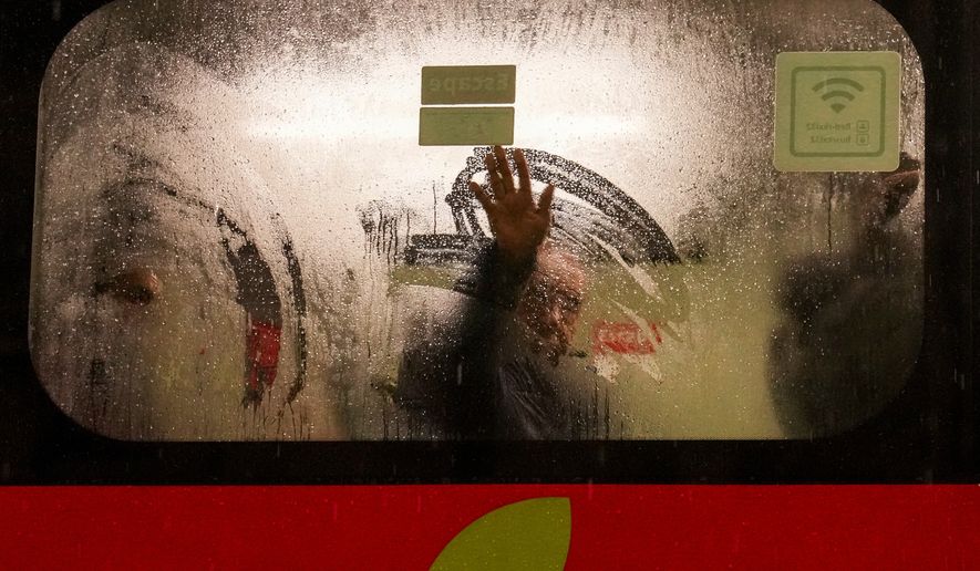 A man on a bus wipes frost from the window during a rainstorm in Santiago, Chile, early Monday, July 20, 2026. (AP Photo/Esteban Felix)