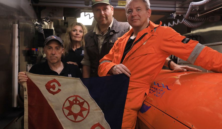 This undated photo provided by the Discovery Channel Tuesday, July 21, 2026, shows, from left, Air/Sea Heritage Foundation (ASHF) President Russ Matthews, ASHF Director Idee Matthews-Montijo, Expedition Unknown's Josh Gates and Deep Sea Visoin President of Operations Craig Wallace inside an AUV hangar with an Explorers Club flag. (Discovery Channel via AP)