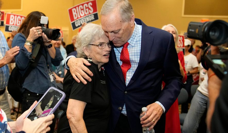 Rep. Andy Biggs, right, R-Ariz., who is running in the primary for Arizona governor, hugs a supporter at a campaign event, Friday, July 17, 2026, in Gilbert, Ariz. (AP Photo/Ross D. Franklin)