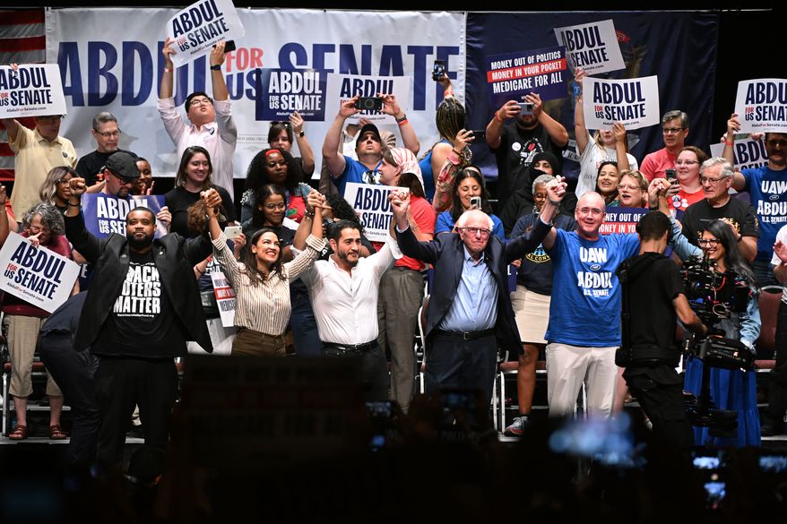 From left foreground, Michigan state Rep. Donavan McKinney, D-Detroit, U.S. Rep. Alexandria Ocasio-Cortez, D-N.Y., Michigan Democratic U.S. Senate primary candidate Abdul El-Sayed, U.S. Sen. Bernie Sanders, I-VT., United Auto Workers President Shawn Fain, and U.S. Rep. Rashida Tlaib, D-Mich. join hands together following a campaign rally for El-Sayed, Saturday, July 18, 2026, in Detroit. (AP Photo/Jose Juarez)
