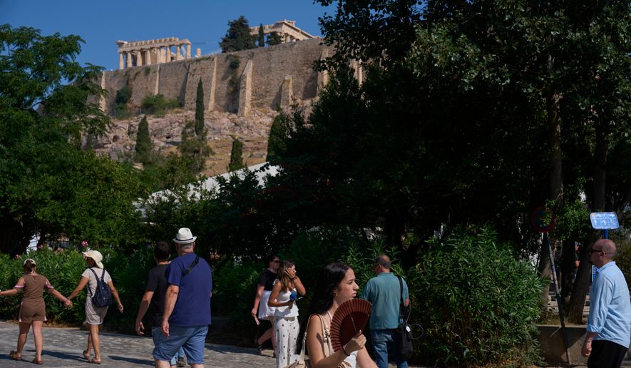Tourists walk near the Acropolis in Athens, Greece, Tuesday, July 21, 2026, after two tourists were stabbed and injured nearby in an attack on a pedestrian street near the entrance to the archaeological site. (AP Photo/Petros Giannakouris)